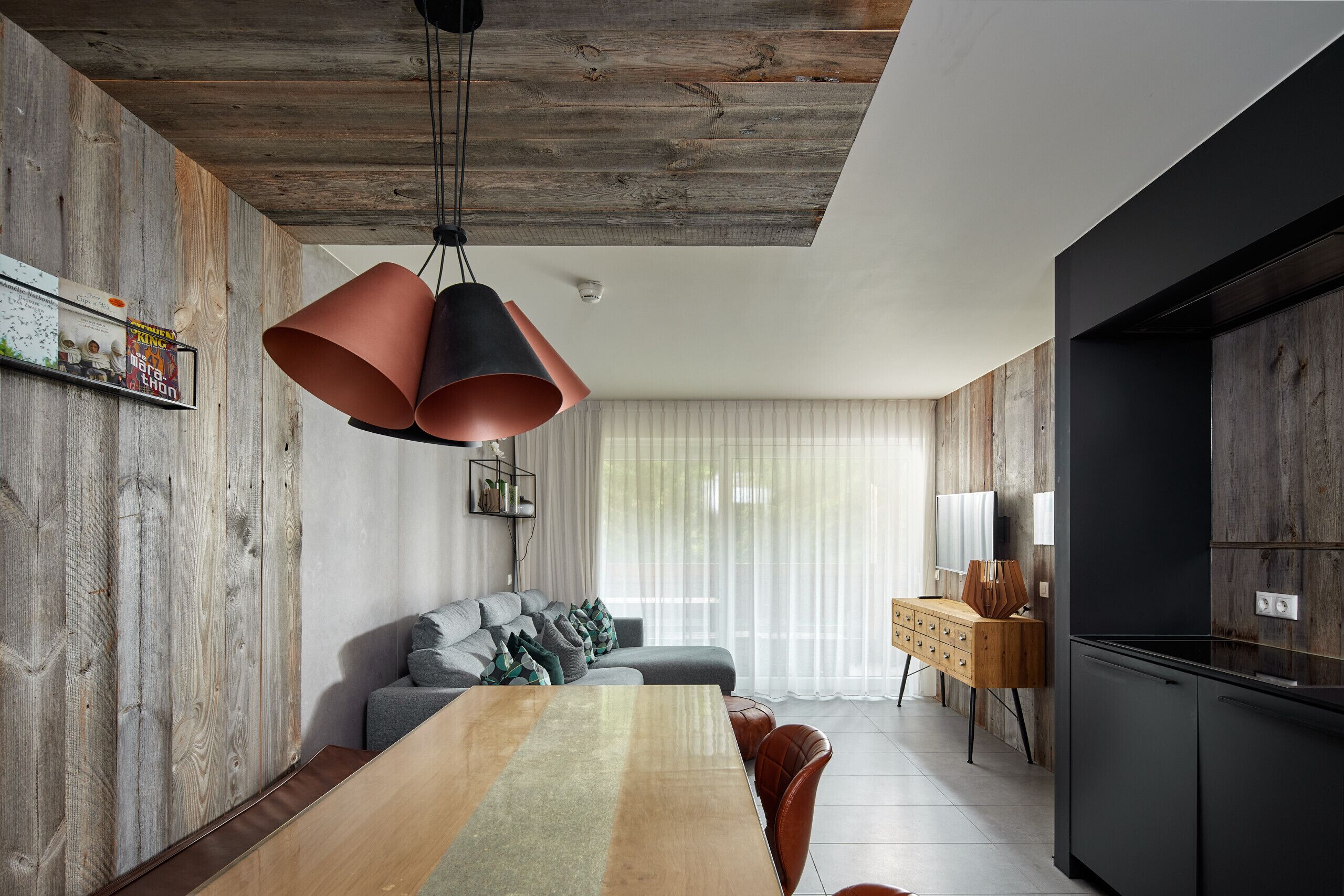 A modern kitchen with a wooden ceiling, a dining area with a long table, and a built-in oven.