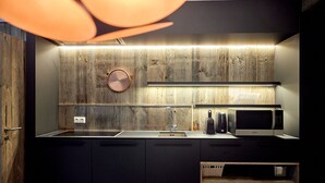 A modern kitchen with a wooden backsplash, a sink, a microwave, and a clock.