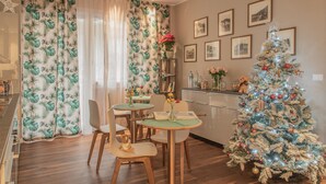 Un comedor con un árbol de Navidad, sillas de madera y una mesa con un jarrón de flores.