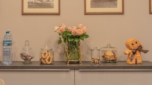 Una encimera con una botella de agua, frascos de aperitivos, un florero con flores y una figurita de hombre de jengibre.