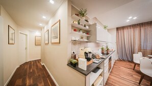 Una cocina moderna con suelo de madera, armarios blancos e isla integrada con pileta y encimera.