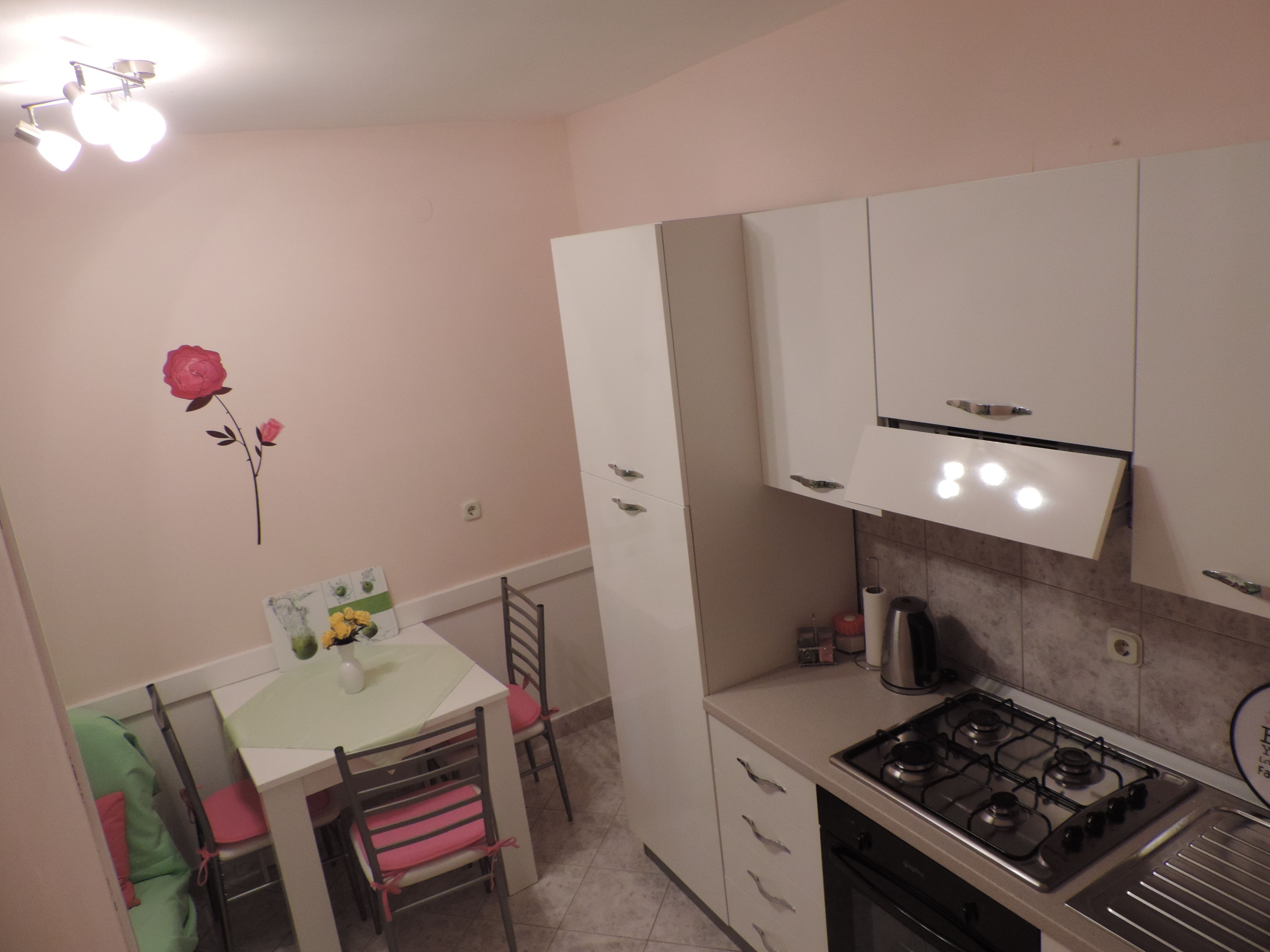 A kitchen with white cabinets, a gas stove, and a dining table with chairs.