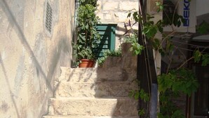 A stone staircase leading up to a building with a metal railing and potted plants. - Apartment Pera (Split)
