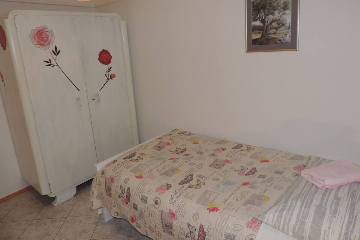 A bedroom with a bed, a dresser, and a framed picture on the wall.