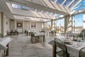 A spacious dining area with multiple tables and chairs, large windows, and a high ceiling with skylights. - Hotel Przy Dworze (Lesna Podlaska)