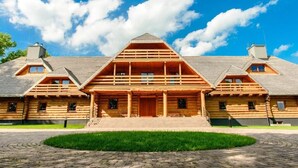 A large wooden log cabin with a central porch and multiple windows. - Hotel Przy Dworze (Lesna Podlaska)
