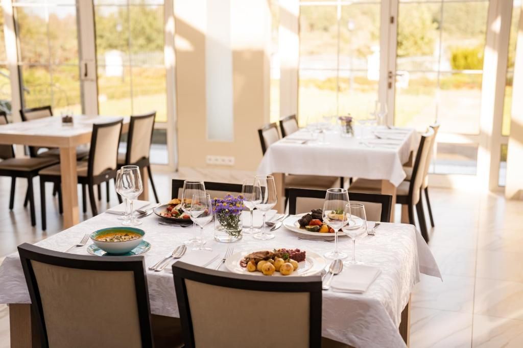 A dining area with tables set for a meal, chairs, and a view of the outdoors.