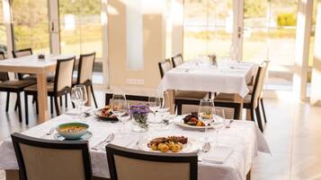 A dining area with tables set for a meal, chairs, and a view of the outdoors.
