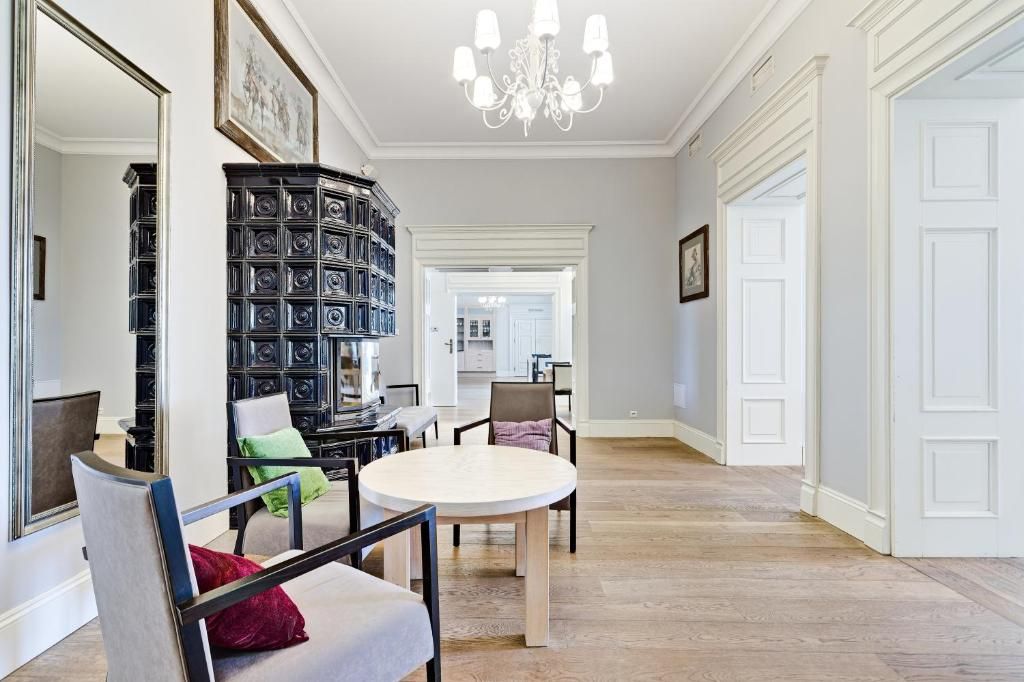 Una habitación amplia con una mesa de comedor redonda, una librería negra y un candelabro.