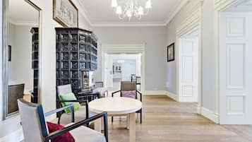 Una habitación amplia con una mesa de comedor redonda, una librería negra y un candelabro.