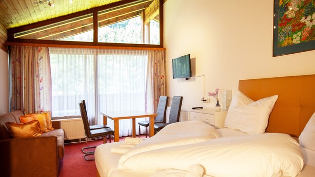 Une chambre d’hôtel avec un grand lit, un canapé, un bureau et un téléviseur fixé au mur.
