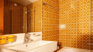 Une salle de bain avec un lavabo blanc, un miroir et une baignoire.