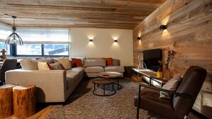 Ein gemütliches Wohnzimmer mit Holzboden, einer Sofagarnitur, einem Couchtisch und einem Fernseher.