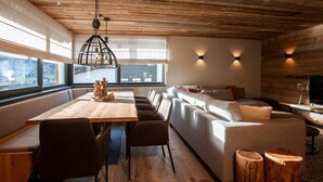 Ein modernes Interieur mit Holzboden, einem Esstisch mit Stühlen, einer Couch und zwei Hockern.