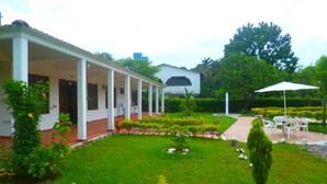 A building with a covered porch, a well-maintained lawn, and outdoor seating area. - Finca Vacacional Villavicencio (Villavicencio)