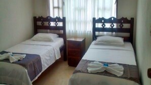 A hotel room with two single beds, each with a wooden headboard, a nightstand, and a window with sheer curtains. - Finca Vacacional Villavicencio (Villavicencio)