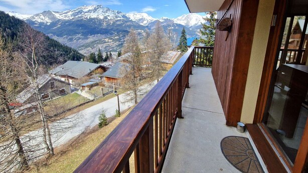 A balcony with a view of snow-capped mountains, a wooden railing, and a glass door. - 3-room apartment for 4/6 people in Valfréjus with balcony (Valfréjus)