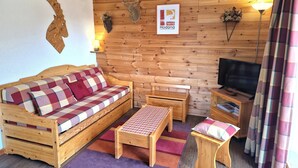 A cozy wooden room with a sofa, a small table, a bench, and a television. - 3-room apartment for 4/6 people in Valfréjus with balcony (Valfréjus)
