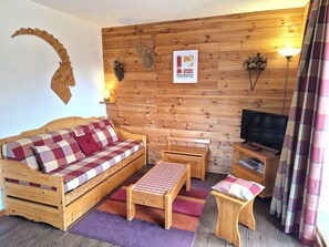 A cozy wooden room with a sofa, a small table, a bench, and a television. - 3-room apartment for 4/6 people in Valfréjus with balcony (Valfréjus)
