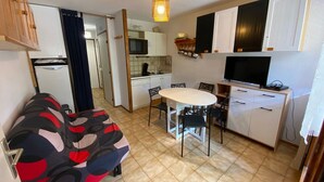 Ein kompakter Wohnraum mit Küchenzeile, Essbereich und einer Couch.