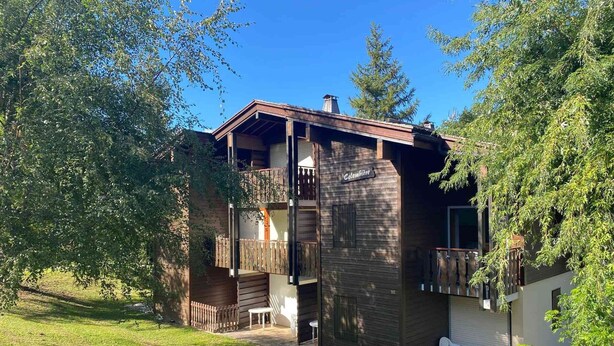 Eine zweistöckige Blockhütte mit einem Balkon und einer kleinen Terrasse.