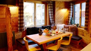 Una habitación acogedora de estilo cabaña, con paredes de madera, una mesa de comedor con sillas amarillas y un sofá con una manta de piel.