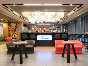 Een moderne bar met neonverlichting, zitplaatsen en een boekenplank.