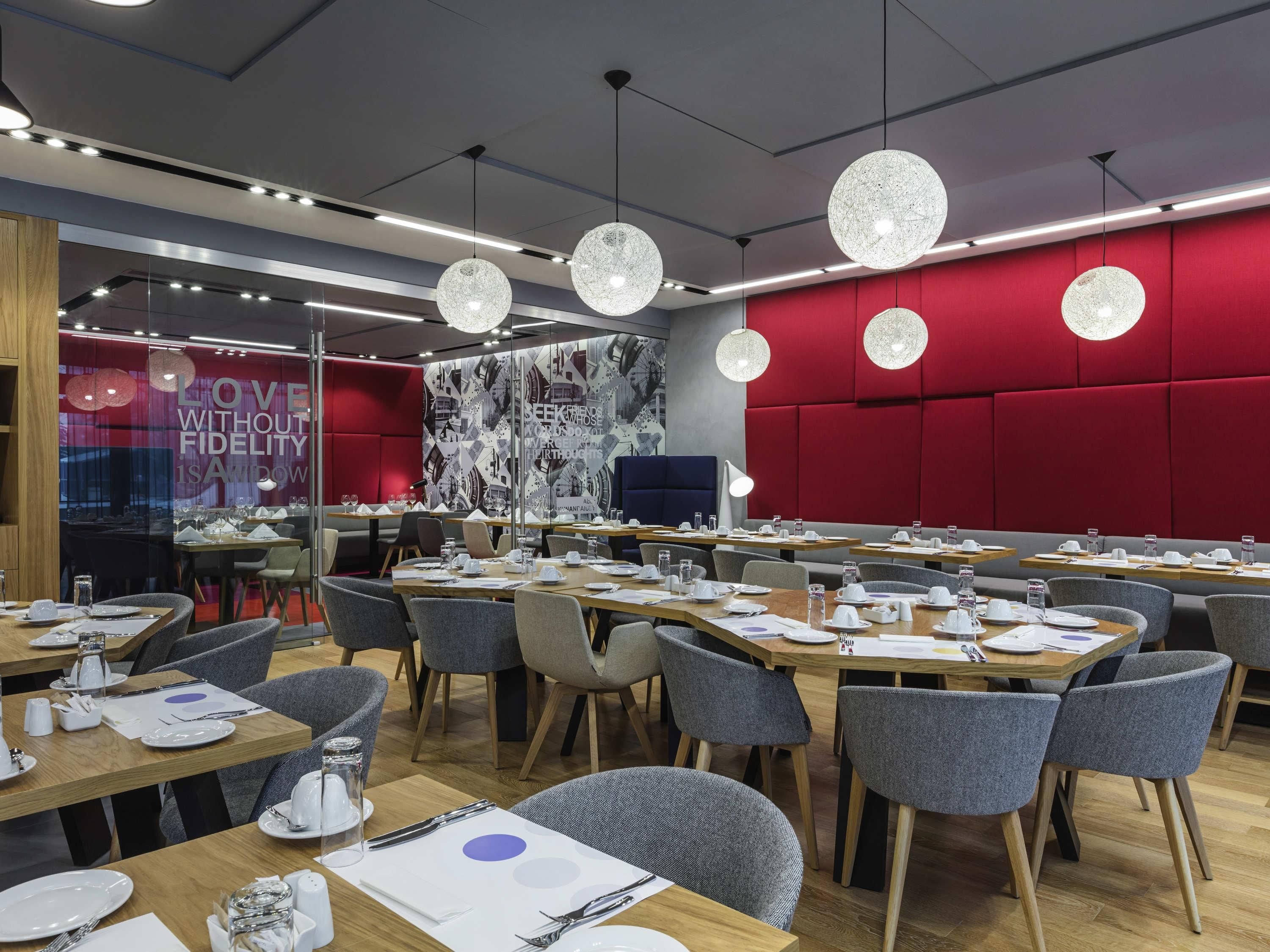 A modern dining area with round tables, grey chairs, and pendant lighting.
