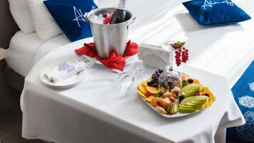 Habitación de hotel impecable con una cama, una mesita de noche con una bandeja de frutas, una botella de champán y una copa.