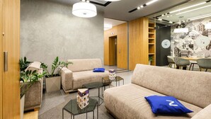 A modern interior with sofas, a coffee table, and a dining area. - Novotel Almaty City Center (Almaty)
