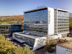 A modern hotel with a glass facade, a flat roof, and a sign reading 'NOVOTEL.' - Novotel Almaty City Center (Almaty)
