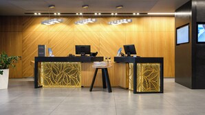 A reception area with two reception desks, a small table, and a potted plant. - Novotel Almaty City Center (Almaty)