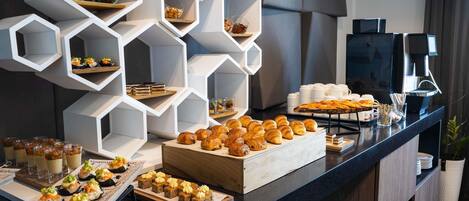 A buffet with various food items and a coffee machine.