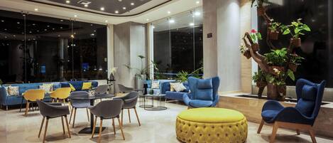 Un área de descanso moderna con un sofá azul, un reposapiés amarillo y diferentes sillas.