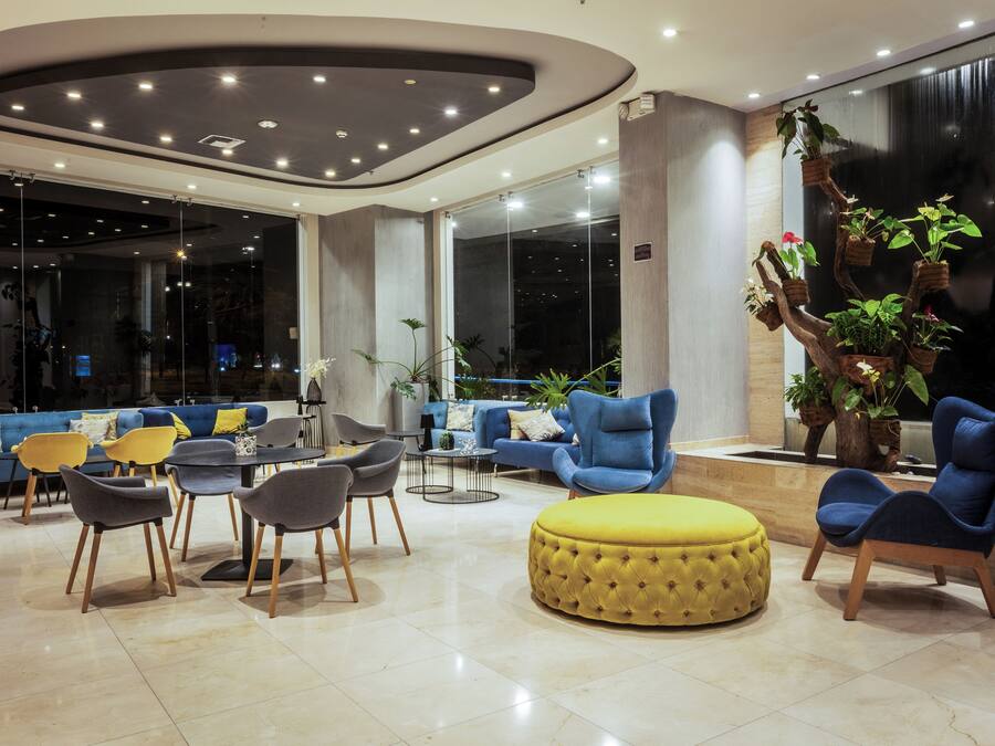 Una moderna area lounge con un divano blu, un poggiapiedi giallo e diversi modelli di poltrone.