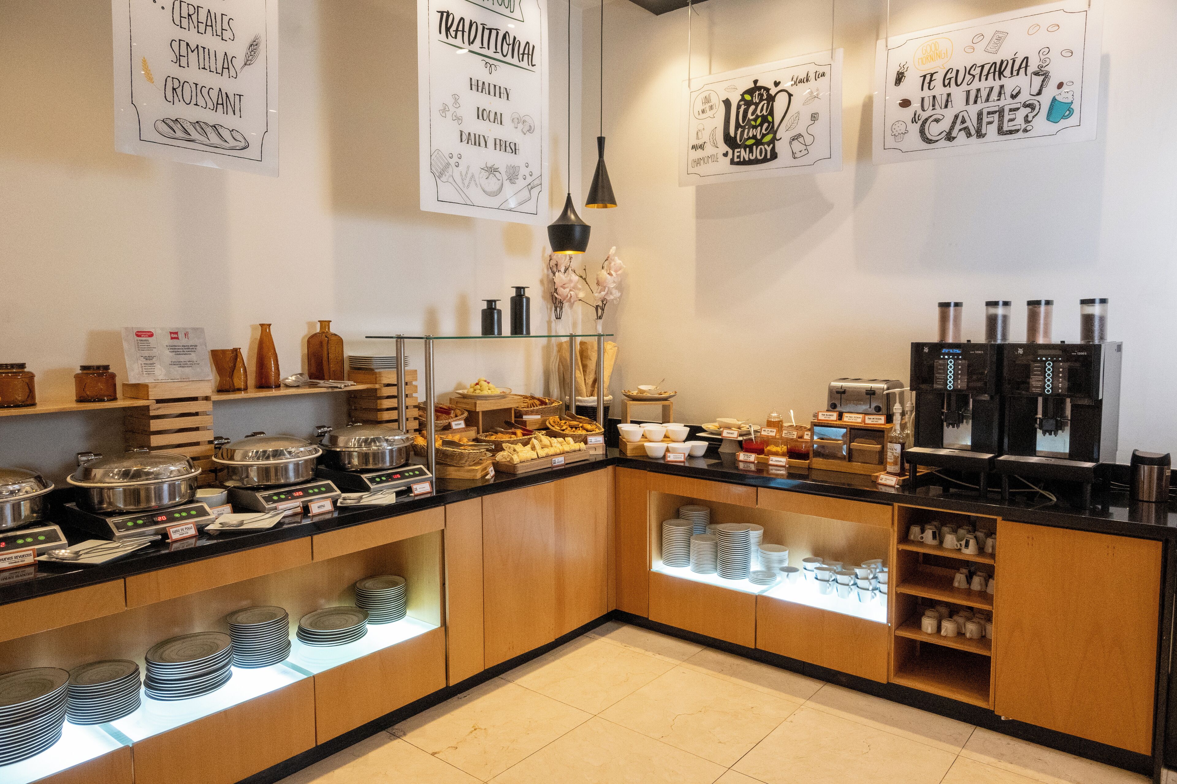 Un bufé de desayuno con diversas opciones de comida y máquinas de café.