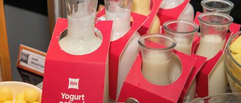 Un bufé con diversos alimentos, entre ellos yogur, queso y frutas.