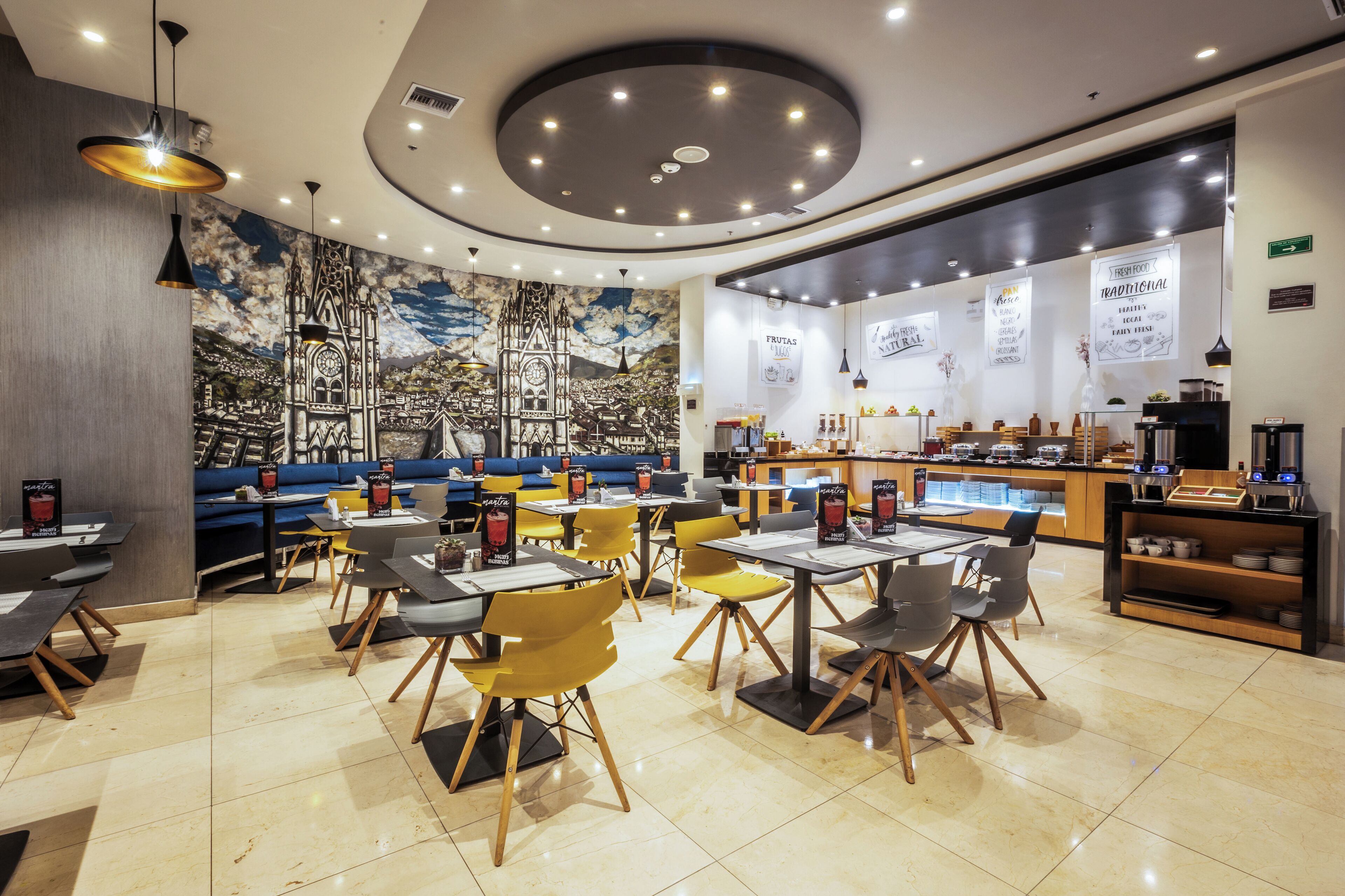 A restaurant with a mural of a cityscape, tables and chairs, and a bar area.