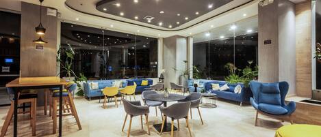 Un lobby moderno con una mesa redonda, sillas, sofás y un sillón azul.