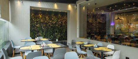 A modern dining area with tables set for two, featuring grey chairs and yellow placemats.
