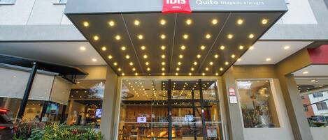 The entrance to ibis hotels with a modern design, glass doors, and a well-lit facade.