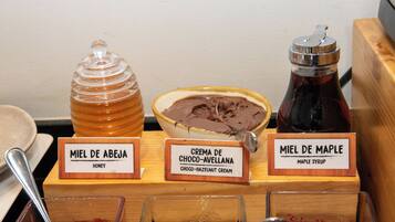 A display of three honey jars labeled 'Miel de Abeja' (honey), 'Crema de Choco-Avellana' (choco-hazelnut cream), and 'Miel de Maple' (maple syrup).