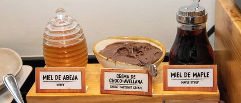 Exhibición de tres tarros de miel: uno etiquetado 'Miel de Abeja', otro con 'Crema de Choco-Avellana' y un tercero con 'Miel de Maple'.