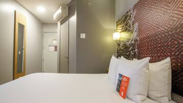 Habitación de hotel con cama, lámpara de pared, puerta y pared decorada con un diseño.