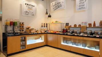 A buffet setup with various food stations, including fruits, juices, cereals, and other breakfast items.