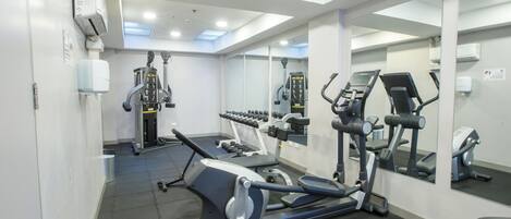 A modern gym with cardio machines, free weights, and mirrors.