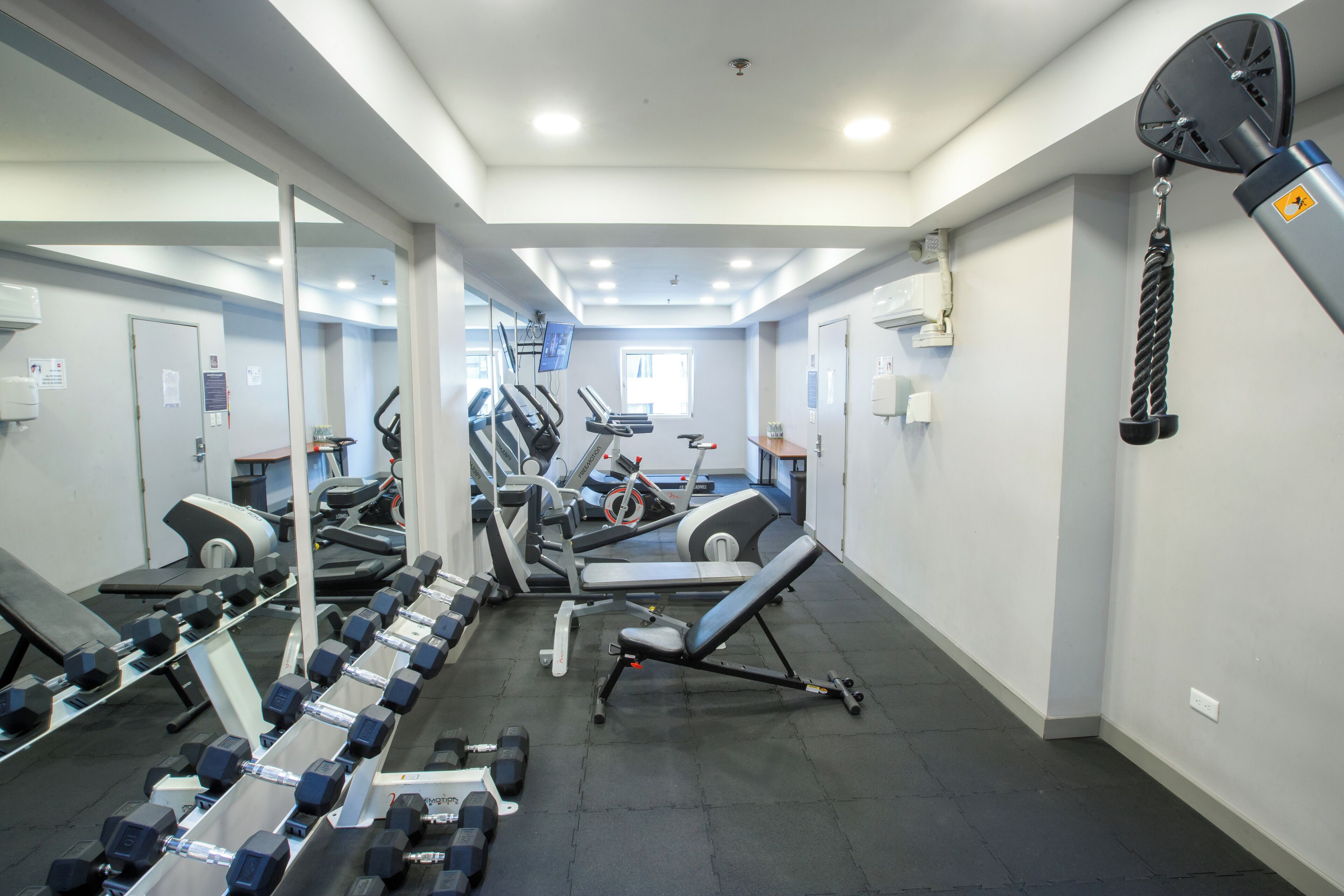 A gym with treadmills, dumbbells, and exercise equipment.