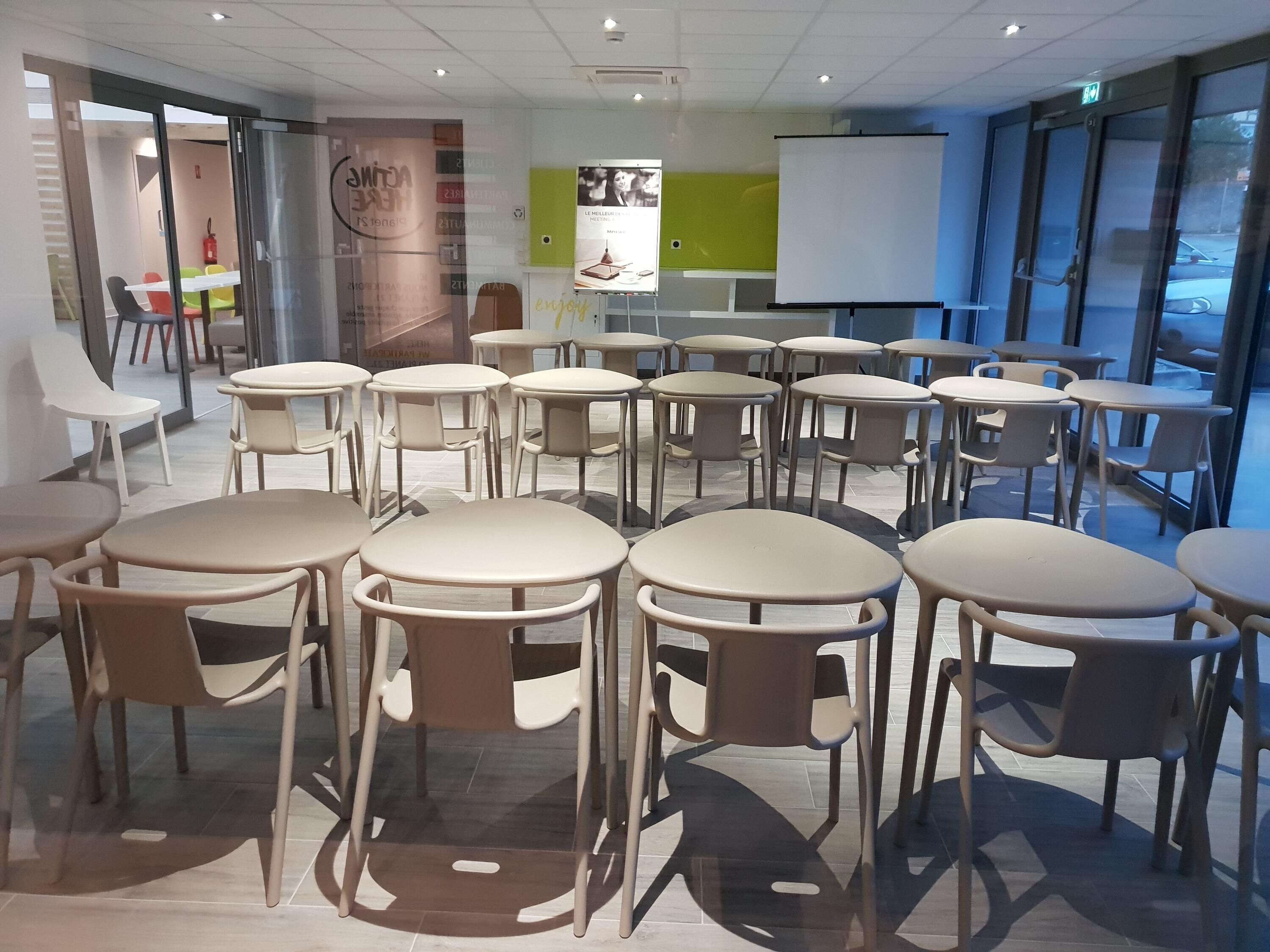 A modern conference room with round tables and chairs, a whiteboard, and glass walls offering a view outside.