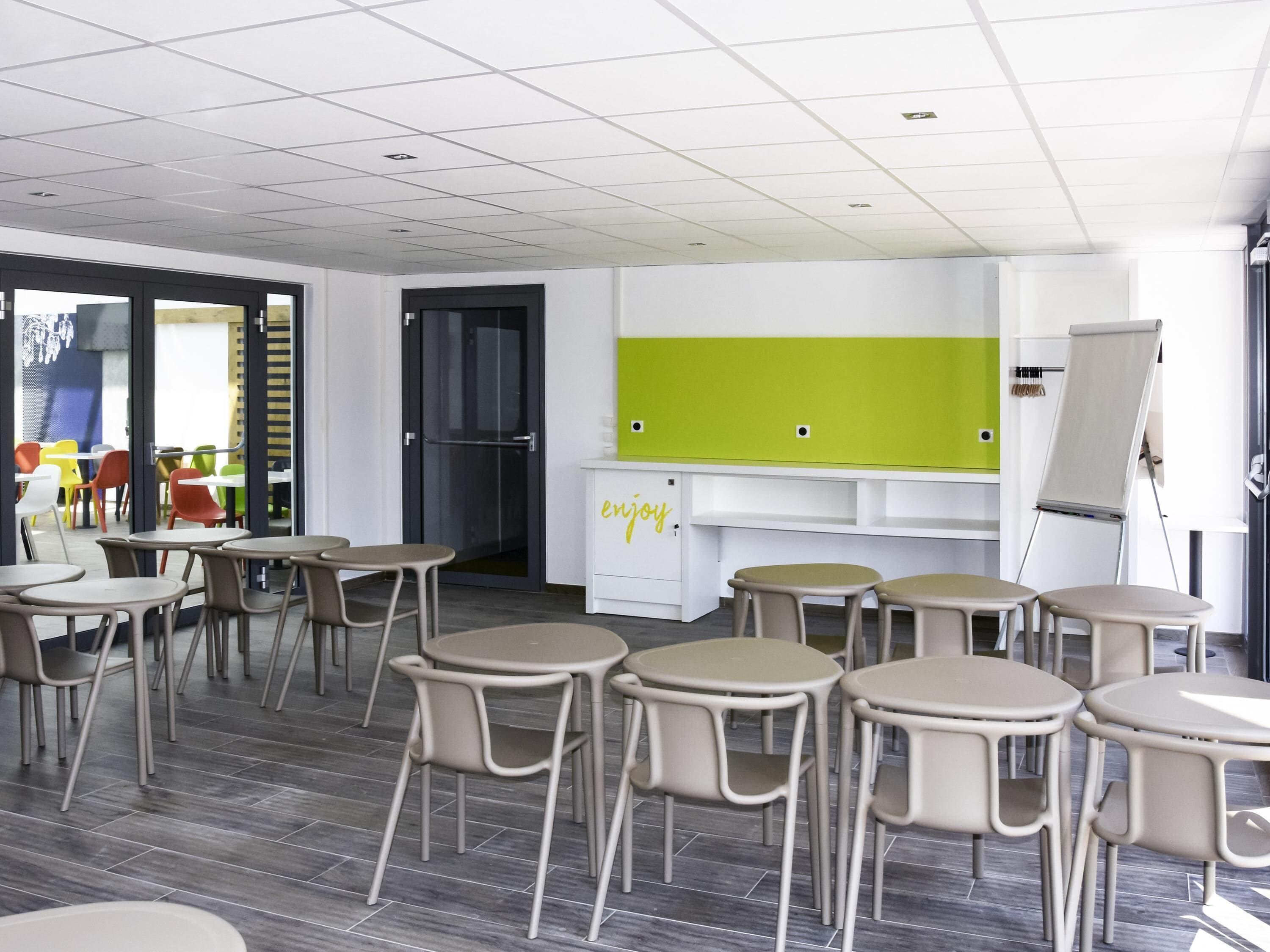Une salle de classe avec des tables et des chaises, un tableau noir et un tableau blanc.