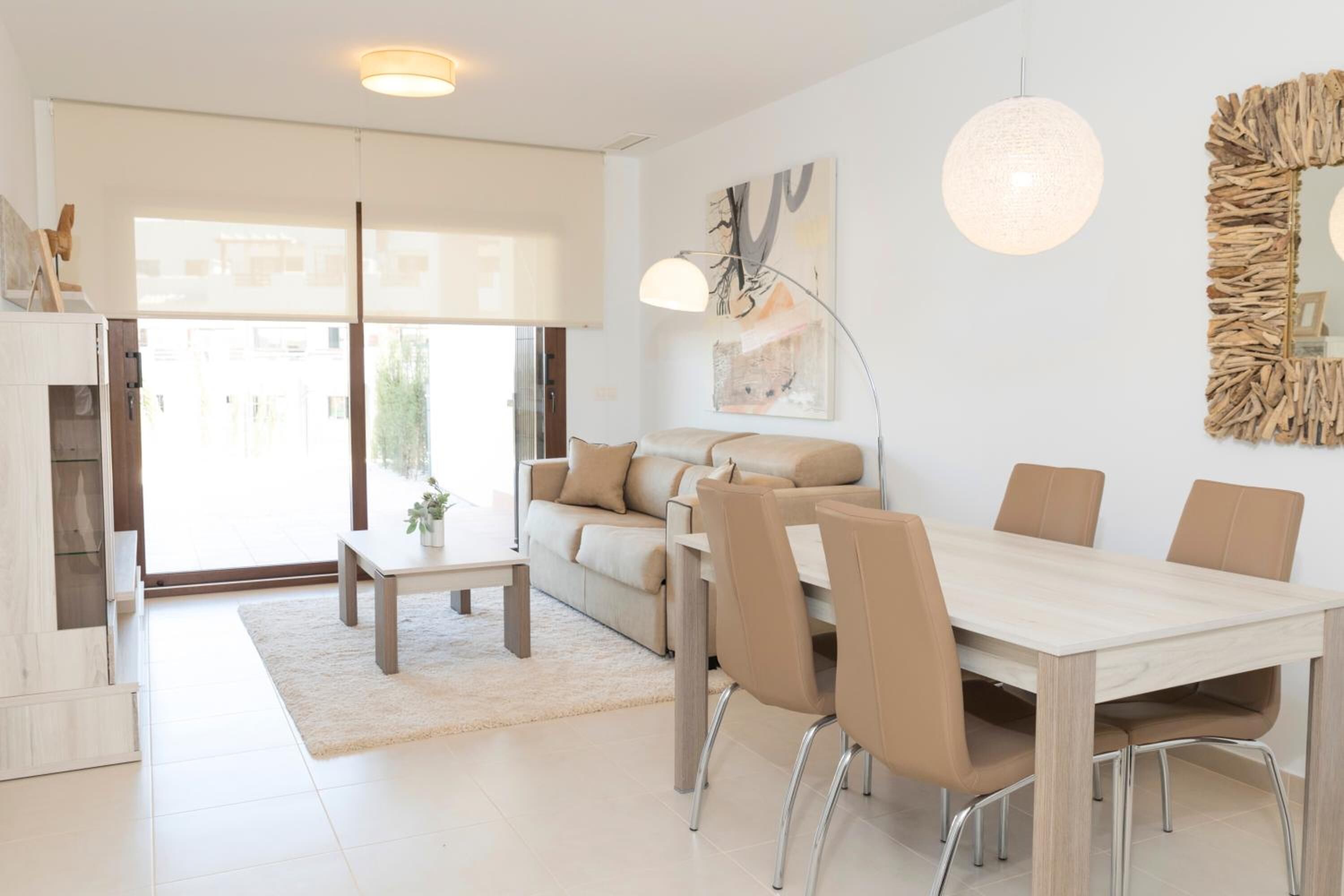 Un salon moderne avec un canapé, une table basse et une table à manger avec des chaises. Il y a une grande fenêtre et un tableau au mur.